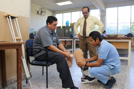 El estudiante del Tec. en Órtesis y Prótesis, Elías Chacón, enseñando a Don Jairo a colocar su prótesis.