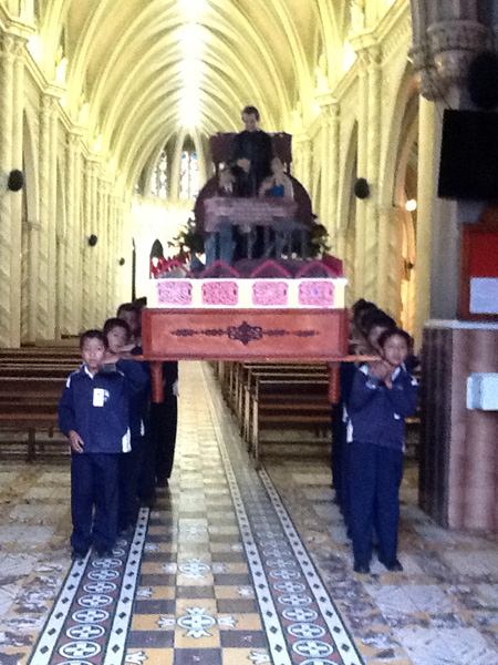 Niños del Colegio cargando a Don Bosco