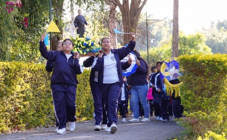 Estudiantes del Centro Escolar Miguel Magone acompa&ntilde;an la imagen de Don Bosco en una alegre caminata hacia la parroquia, expresando su fe y esp&iacute;ritu salesiano.