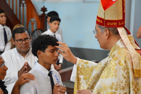 Un joven recibe el sacramento de la Confirmación, sellando su compromiso con la fe y el Espíritu Santo, en la Capilla de María Auxiliadora de Granada.
