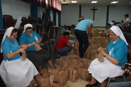 Hijas de María Auxiliadora ayudan a preparar los kits de la Fiesta del MJS. El kit consta de unja capa de lluvia, una pañoleta y una pulsera.