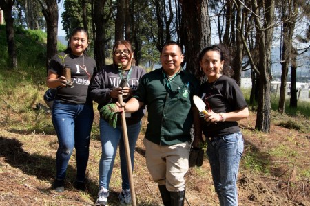 Estudiantes de la Universidad Mesoamericana sostienen árboles listos para ser plantados, en el marco de la jornada de reforestación en el campus de Quetzaltenango.