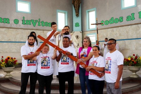 El padre René Guzmán, SDB, bendice a un grupo de misioneros en la parroquia, quienes, una cruz en alto, se preparan para llevar el mensaje de evangelización a diversas zonas de la comunidad.