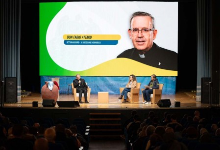 El padre Fabio Attard, XI Sucesor de Don Bosco, saluda y dialoga con los participantes durante la inauguraci&oacute;n de las LIV Jornadas de Espiritualidad de la Familia Salesiana, en el Teatro Grande de Valdocco, marcando el inicio del encuentro bajo el lema del Aguinaldo 2026: &ldquo;Haced lo que &Eacute;l os diga. Creyentes, libres para servir&rdquo;.