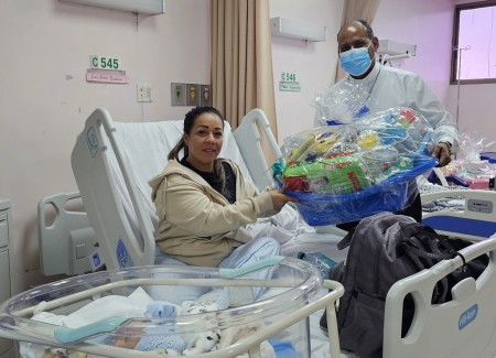 El padre David Panezo, SDB, pastoralista del Instituto Técnico Don Bosco, entrega una de las 56 canastillas con insumos para bebés donadas a la maternidad del Hospital Santo Tomás.