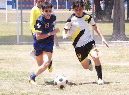 Jugadores de las instituciones participantes disputan el balón durante uno de los encuentros de fútbol en el Primer Día Deportivo Don Bosco 2025, celebrado en Ciudadela Don Bosco. El evento reunió a jóvenes deportistas en un ambiente de sana competencia y fraternidad.