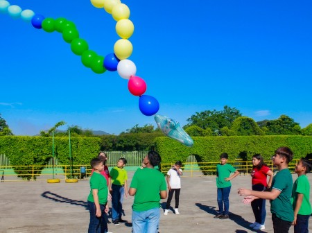 Niños de la Escuela Anexa Don Bosco elevan un Rosario de globos de helio, representando cada continente con su color: verde por África, rojo por América, blanco por Europa, azul por Oceanía y amarillo por Asia, durante la celebración del Santo Rosario Misionero.