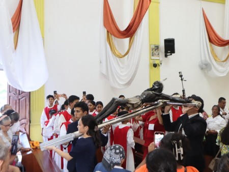 Jóvenes cargan con devoción la imagen del Cristo Negro en la procesión de entrada de la santa misa, uno de los momentos más emotivos de la festividad en Petén, símbolo de fe y unión comunitaria.