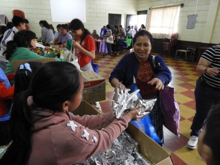 Una de las beneficiarias recibe la bolsa de alimentos entregada por la Obra Social Mamá Margarita, en apoyo a las familias de la parroquia La Divina Providencia.