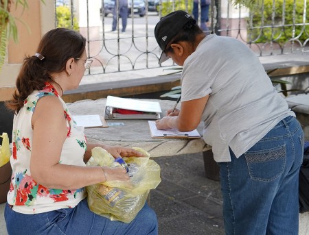 Una de las beneficiadas firma para recibir su bolsa de víveres durante la entrega realizada en marzo en la Parroquia El Espíritu Santo.