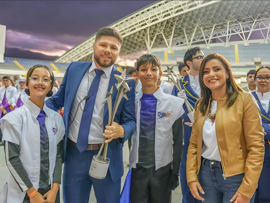 Luis Fernando Solano, director de la banda; estudiantes de CEDES Don Bosco; y Yariela Quirós, vicealcaldesa de San José, celebran el logro tras la espectacular presentación de Forever Rock.