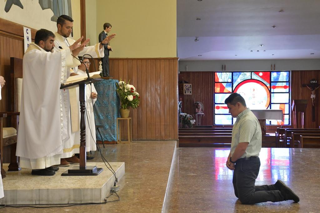 El hermano Daniel Núñez, de rodillas, recibe la bendición del padre Julio Navarro, SDB, durante la misa de envío misionero en el Templo Santo Domingo Savio del Instituto Técnico Ricaldone.