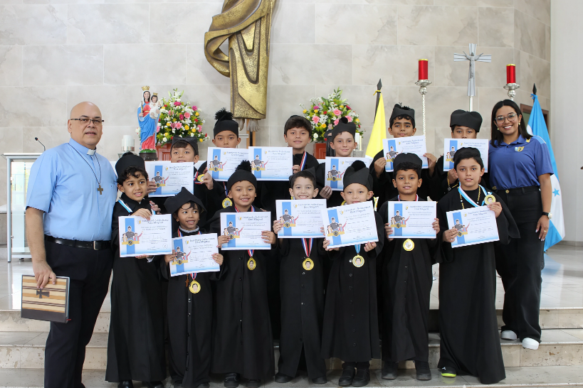 Estudiantes caracterizados como Don Bosco recibieron el reconocimiento “Don Bosco de cada sección”, junto al padre rector Rodolfo Guzmán, SDB, durante la celebración de los 210 años del nacimiento del santo fundador.