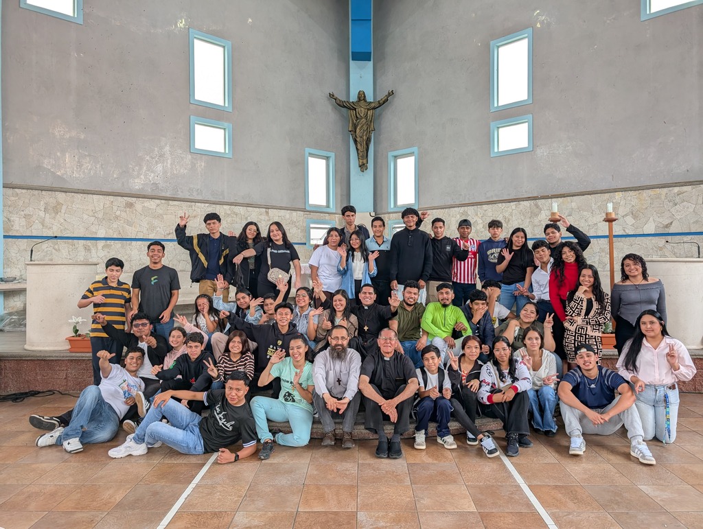 Jóvenes sonrientes posan al finalizar el encuentro del quinto día de la novena a Don Bosco, reflejando la alegría y el espíritu fraterno que caracteriza al carisma salesiano.